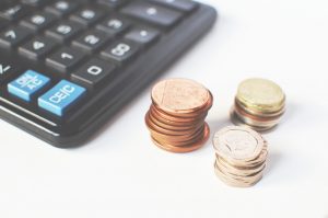 black calculator, 3 small stacks of coins to the right, used to showcase budgeting 