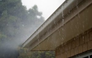 Photograph of a house gutter overflowing from a rainstorm. 
