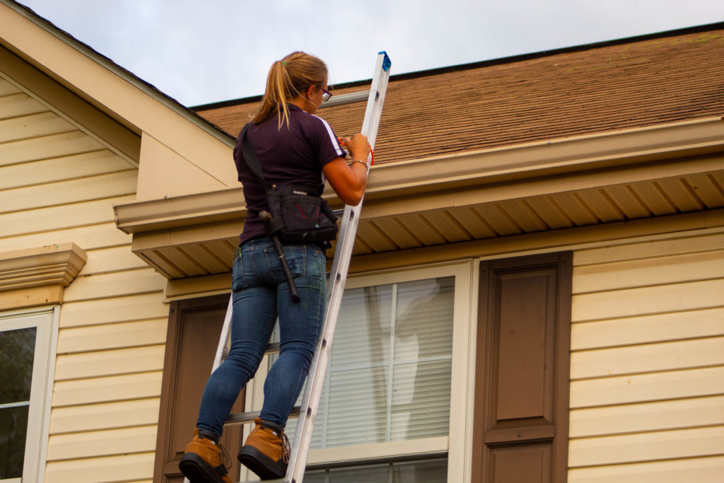 woman climbing ladder leaning against home